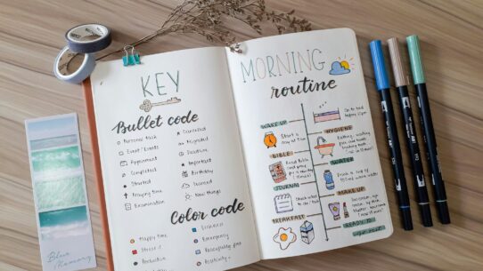 an open book with writing on it next to a pair of scissors